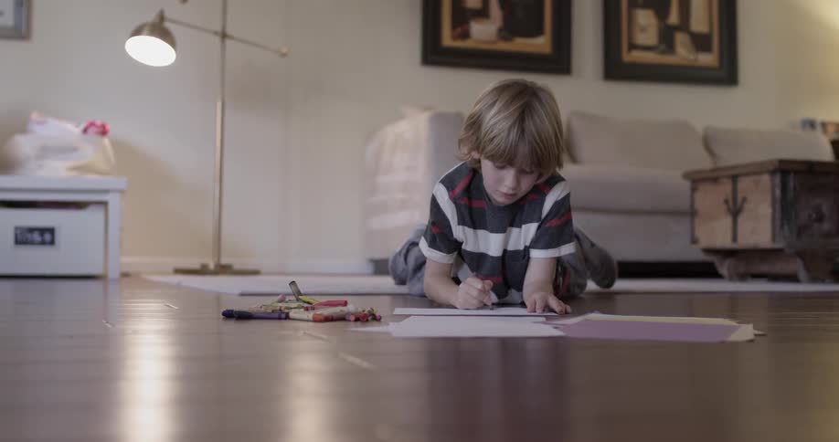 A child is coloring pictures on the floor