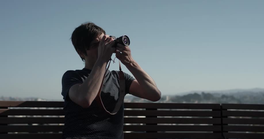 Man sits on a bench taking a picture