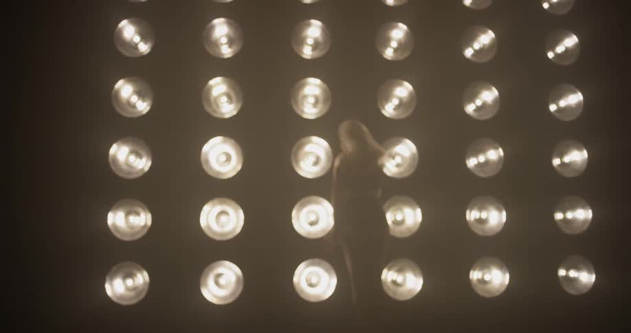 A woman is posing in front of lights in a dark room