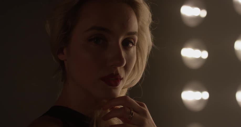Woman in black looking at the camera in front of lights