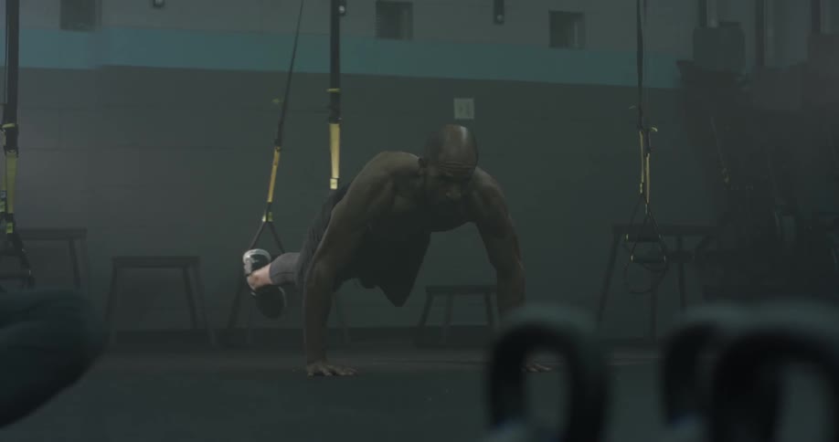 A man works out his legs by holding himself up as he suspends his legs with straps