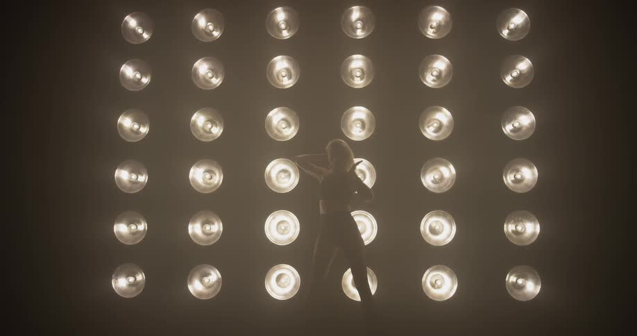 A woman dances in front of a wall of lights
