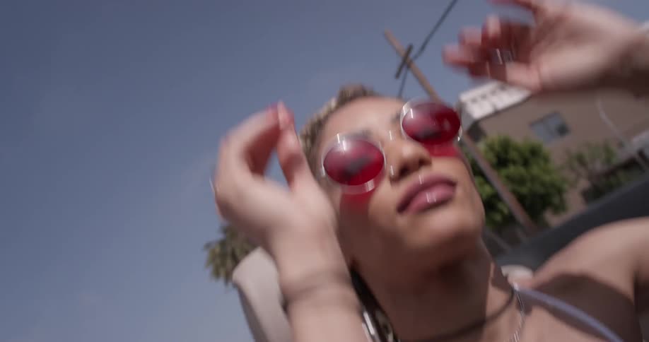 Woman with red sunglasses dancing in a convertible