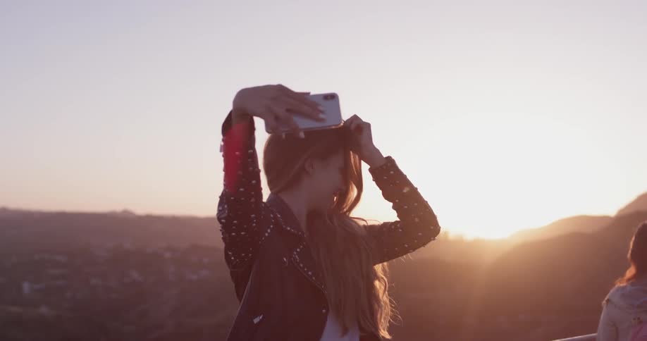 A woman taking a selfie at the top of a mountain