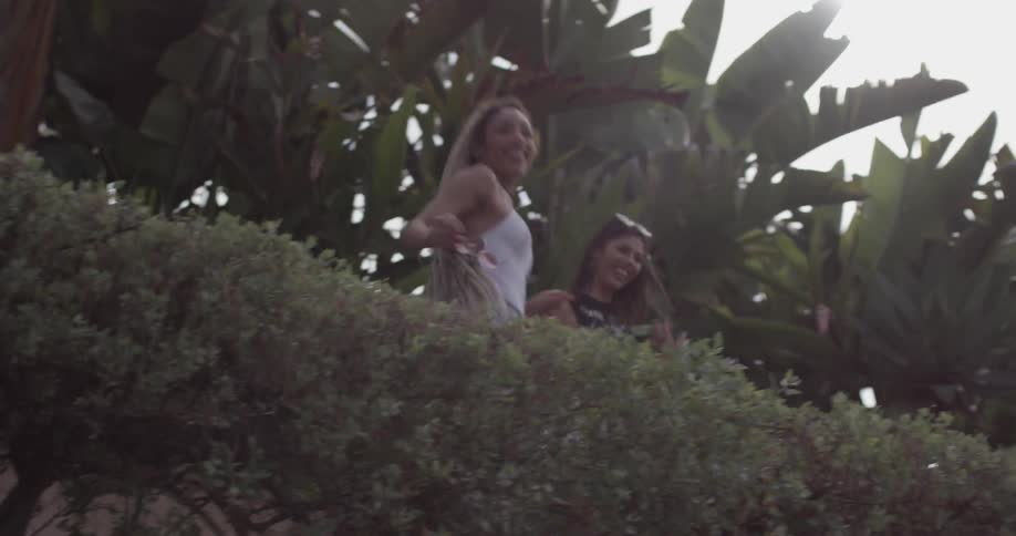 Two women dancing as they walk down the sidewalk