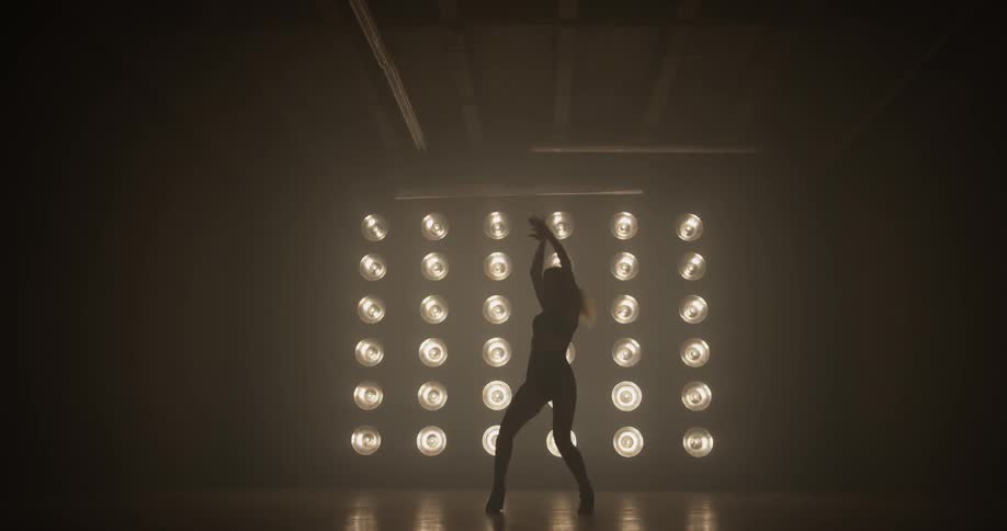 A woman dancing on stage in front of bright lights