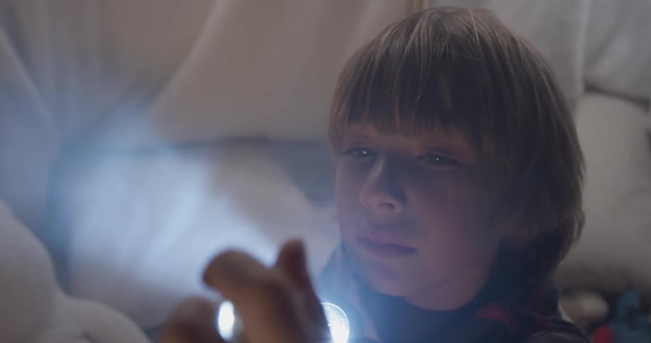 Boy smiles while shining a flashlight through a transparent gem