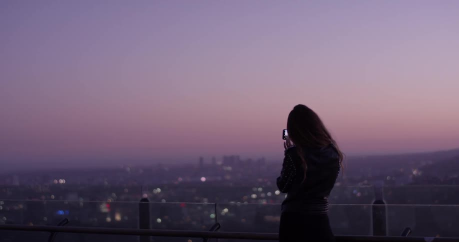 Woman records the city below with her phone