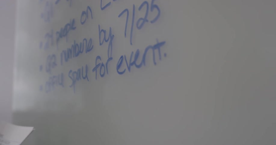 A woman writes with a blue marker on a dry erase board