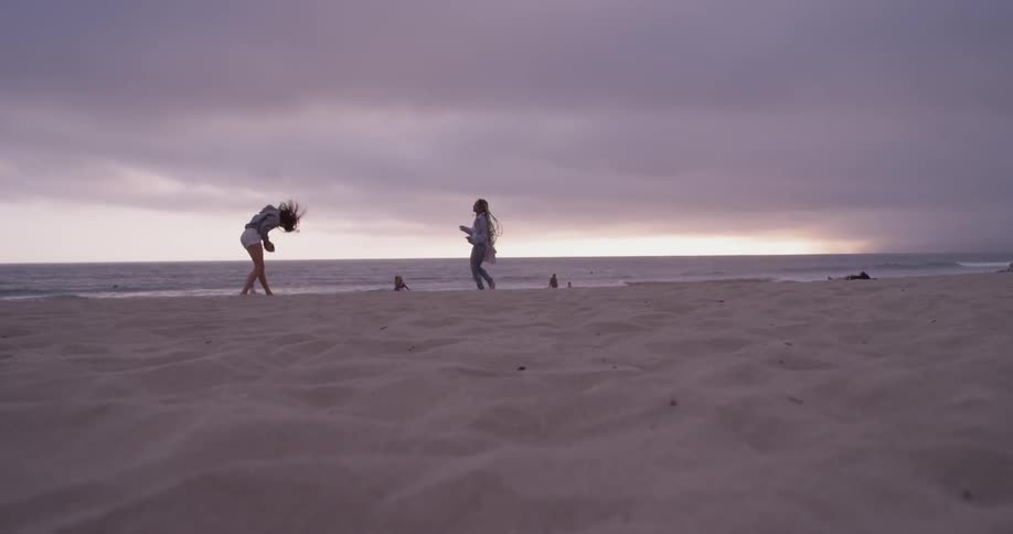 Two women playing catch on the beach