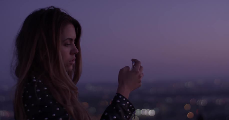 Woman looks through a camera with a city below