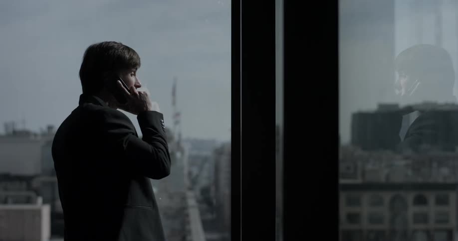 Businessman talks on phone while staring out window