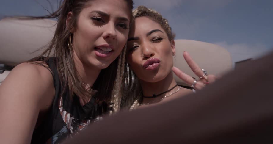 Two women sitting in the back of a convertible