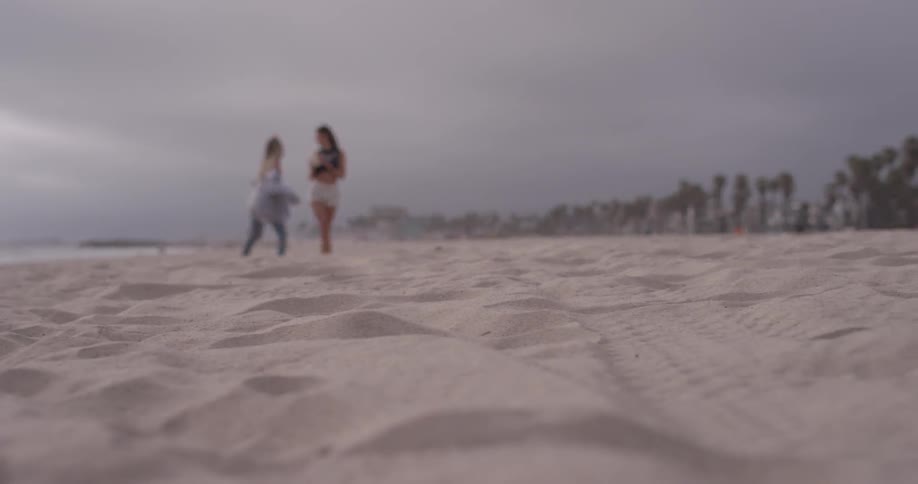 Two women walk on the beach on a cloudy day