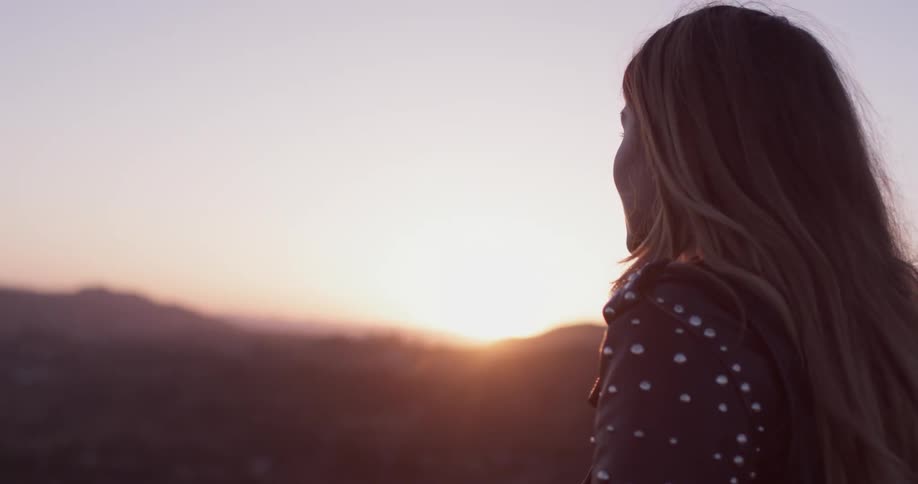 A woman looking at the sunset from the top of a mountain