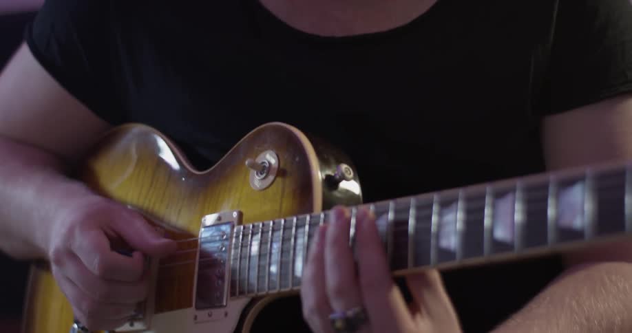 Man plays guitar and bobs head up and down