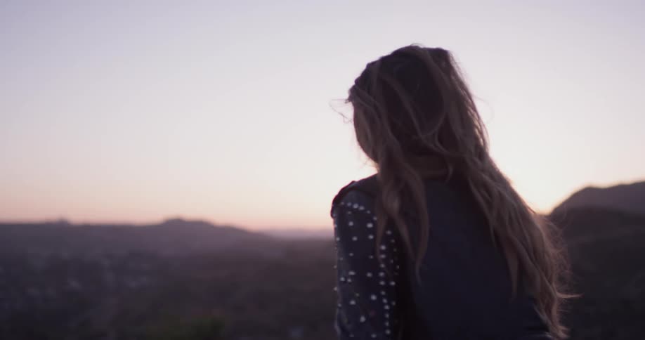 Woman looks out at the city below at sunrise