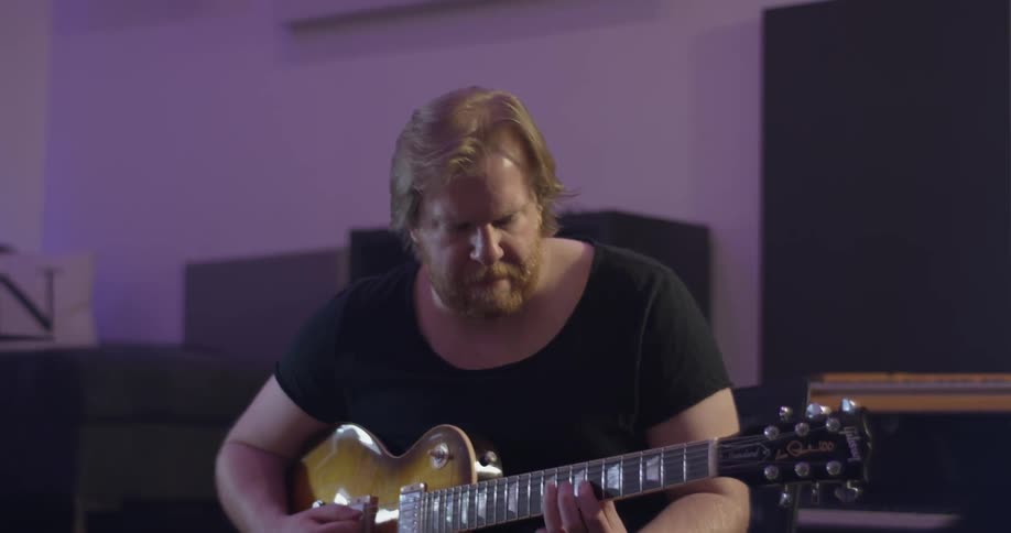 A man playing a guitar in a studio