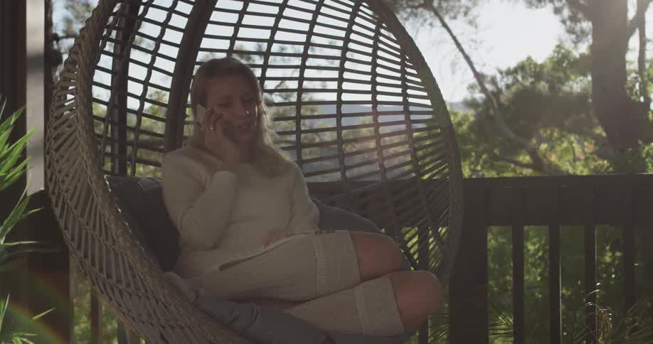 Woman talks on the phone while sitting in a small circular swing
