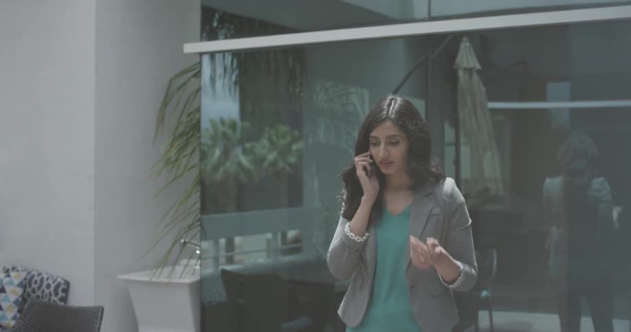 A woman paces while talking on the phone outside
