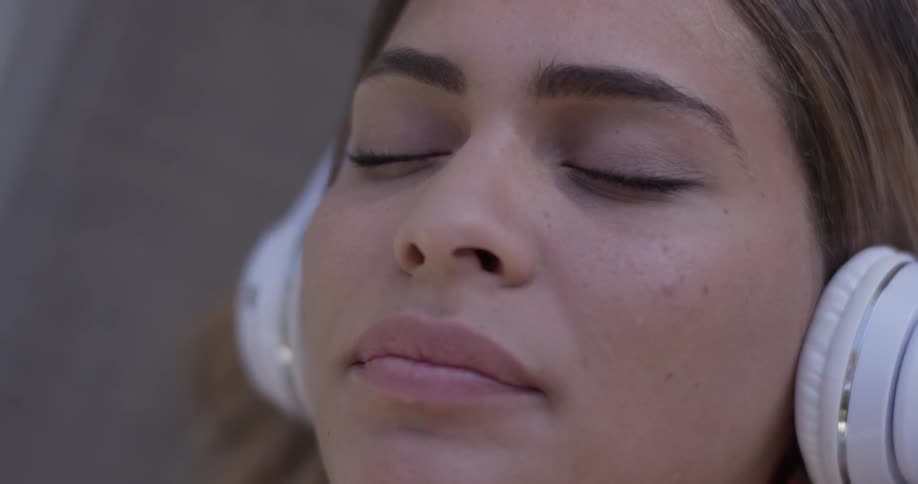 Woman wearing headphones lays down with eyes closed