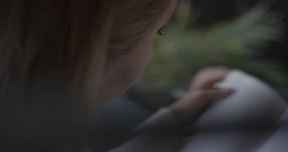 A woman is sitting down while reading a book