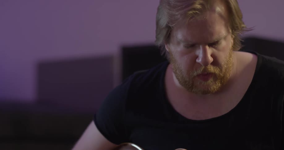 A man playing a guitar in a studio