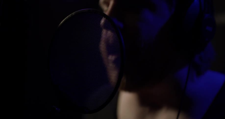 A man singing into a microphone in a studio
