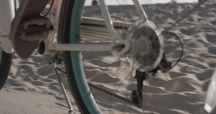 Closeup of a woman's feet pedaling a bike on a path at the beach