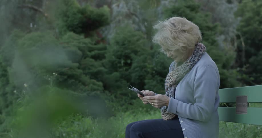 Woman sits on bench and looks at photographs