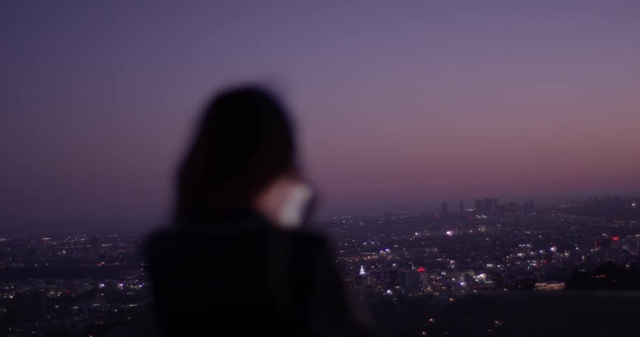 Woman takes videos with her phone at the city below