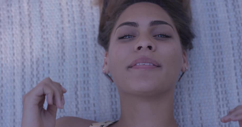 A woman lays on her back smiling and playing with her hair
