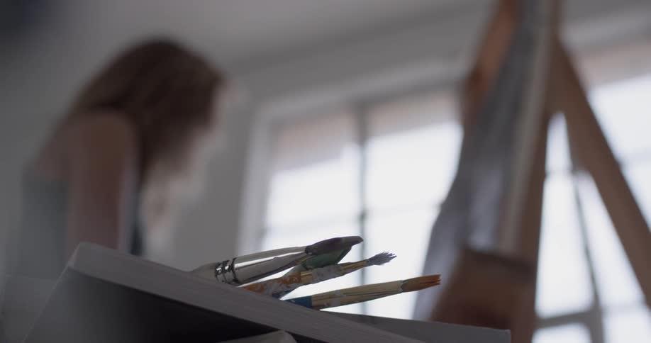Paintbrushes hang off the edge of a table