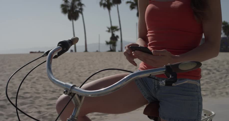 A woman is sitting on a bicycle looking at her phone