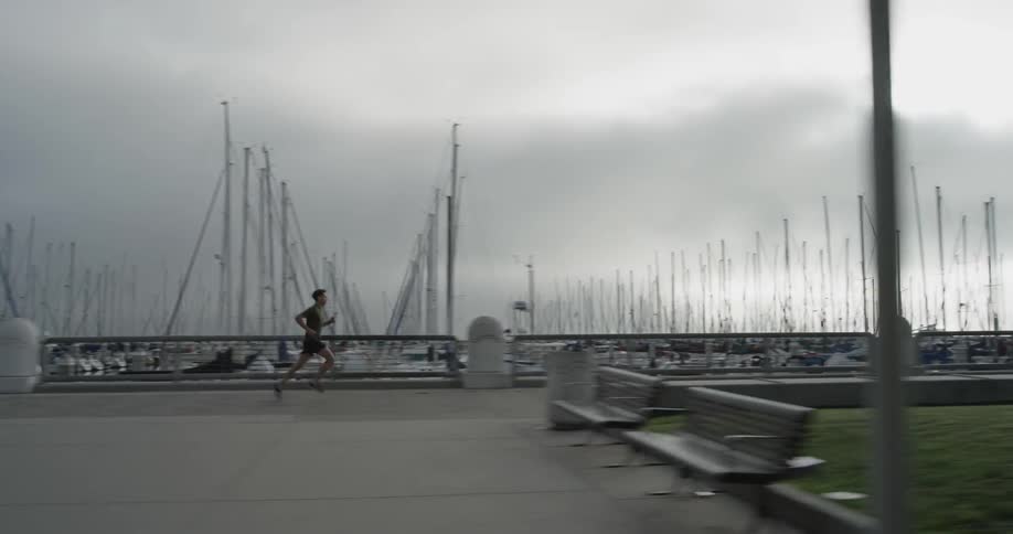 Man jogs near a harbor filled with boats