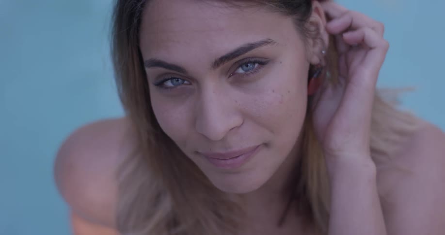A woman is smiling and moving her hair behind her ears
