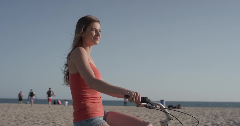 Woman riding a bicycle next to the beach