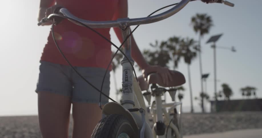 Woman walking a bicycle down a sidewalk