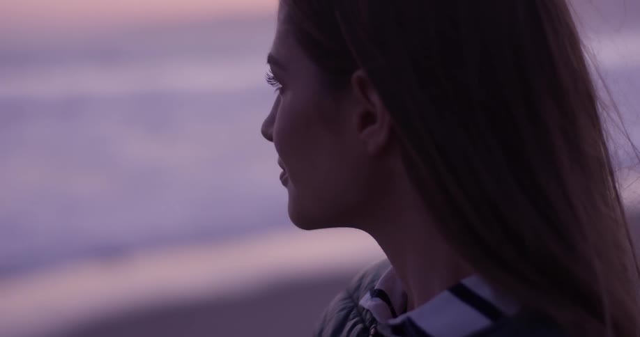 Woman standing at the beach at sunset