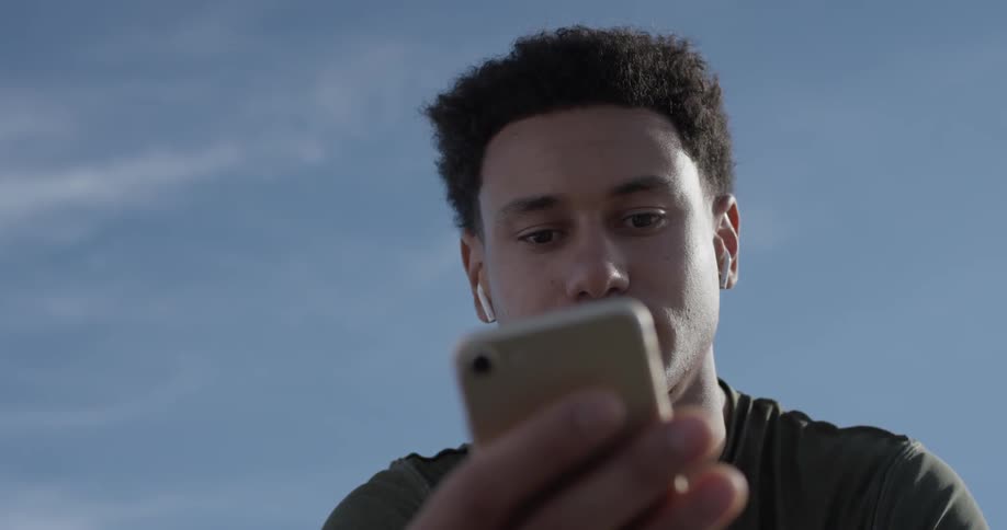 Man sitting around outside texting on a phone