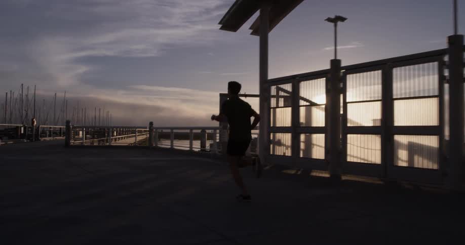 A man running around a track at sunset