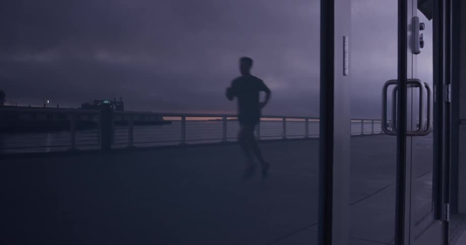 Man runs on sidewalk near marina at night