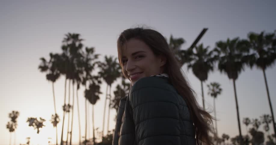 Top part of a woman walking outside in a jacket and playing with her hair