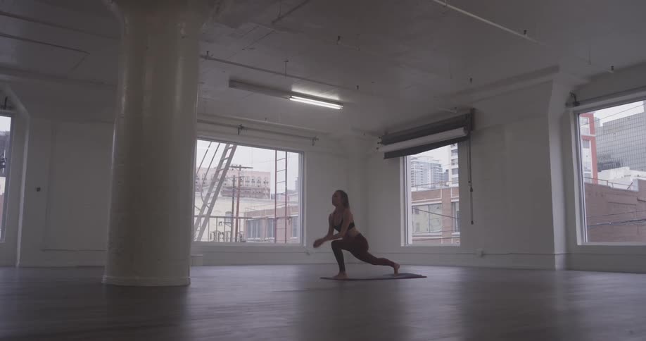 A woman stretches her leg high into the air, then places it down on the floor