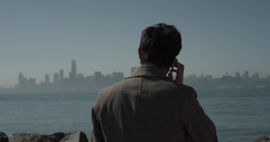 Man using a cell phone along some rocks