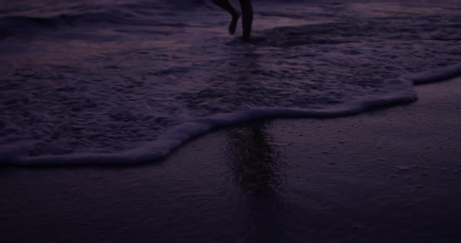 A woman walks along the beach near the water
