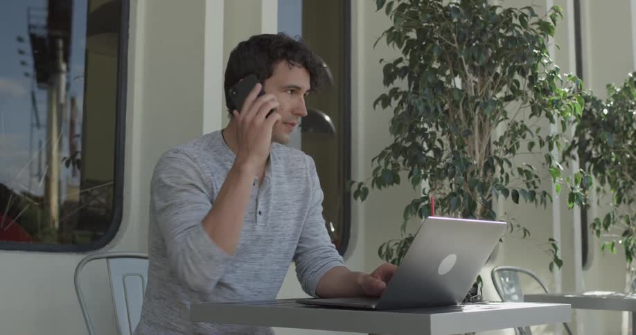 Man types on computer while sitting outside at table