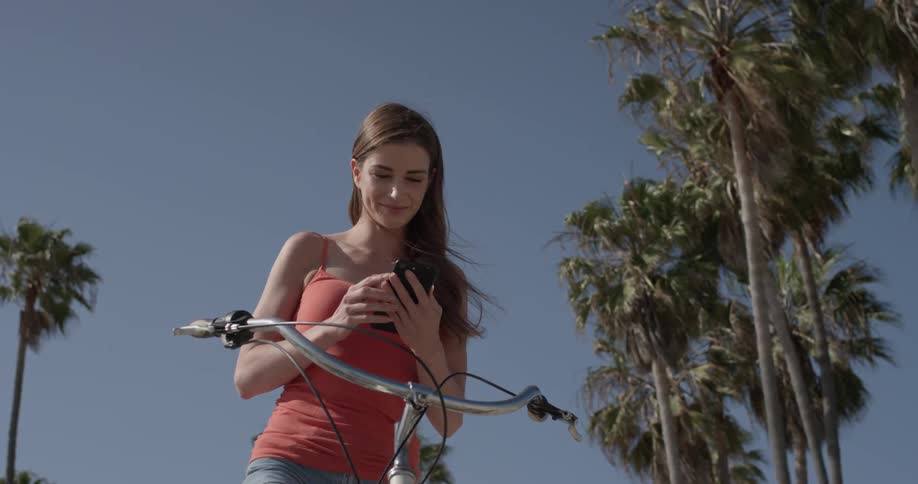 A woman is on a bike looking at a phone