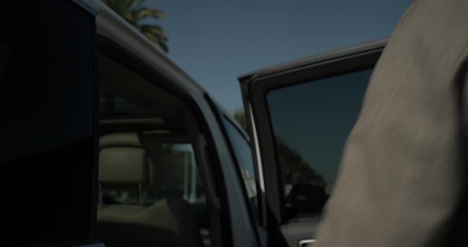 A man opens the back door of an suv and gets in closing the door behind him
