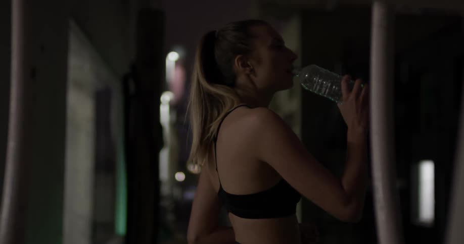 Woman in sports bra drinks from water bottle